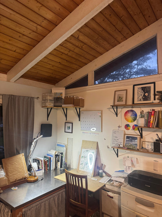 A corner art and office space with a desk, shelves and chair